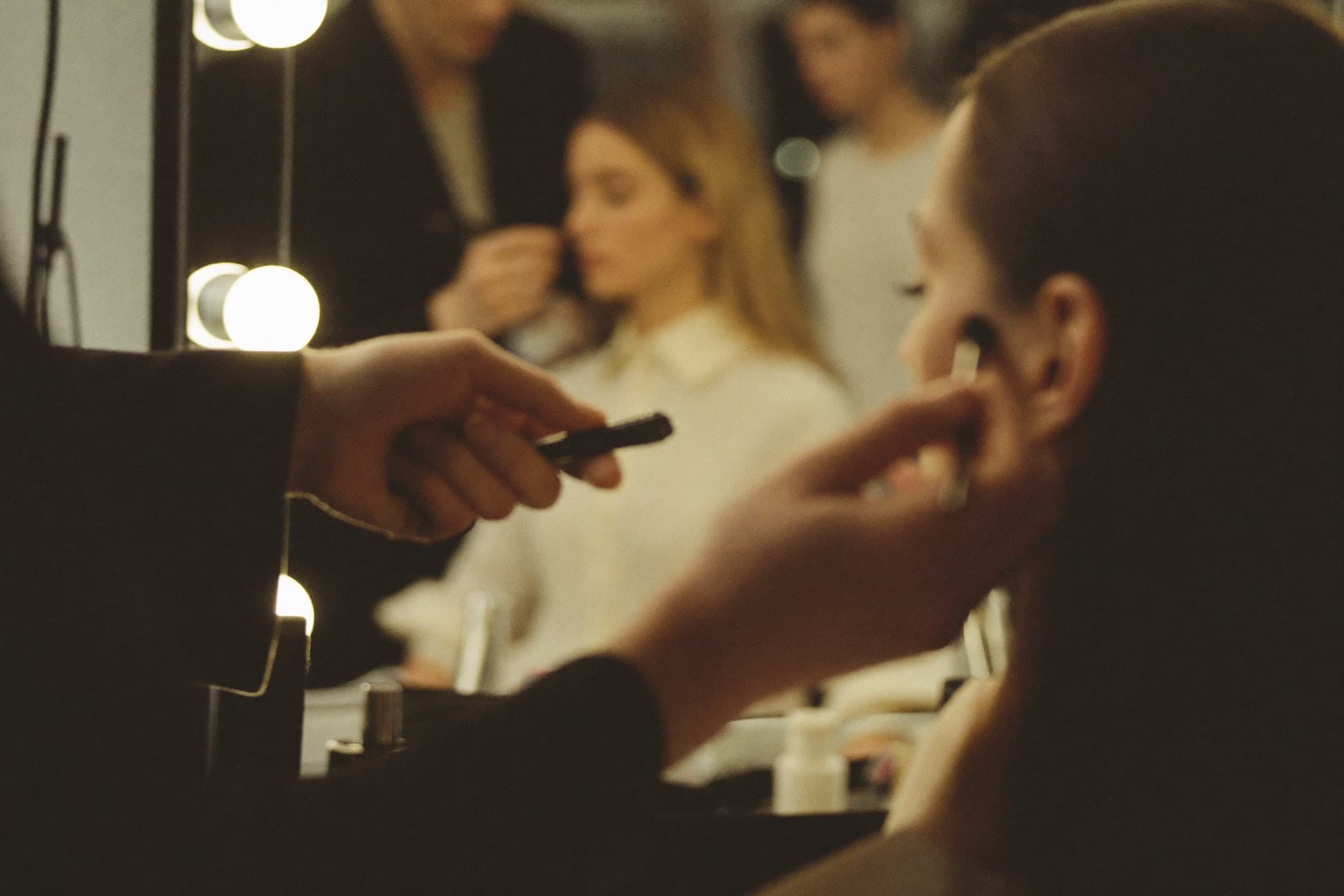 Backstage at a fashion shoot, makeup being applied at a mirror